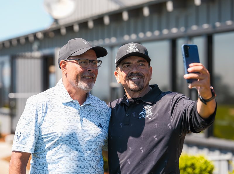 Two brothers in tournament caps line up a selfie outside the clubhouse