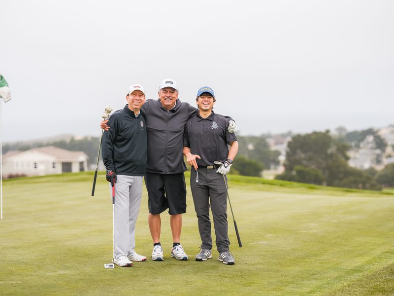 Three brothers cracking up arm in arm on the green