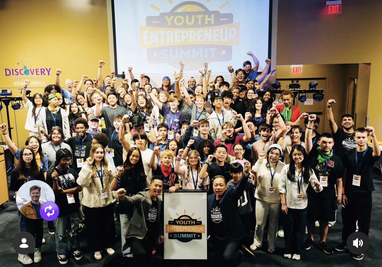 A group cheering beneath a Youth Entrepreneur Summit projection at a past YES program